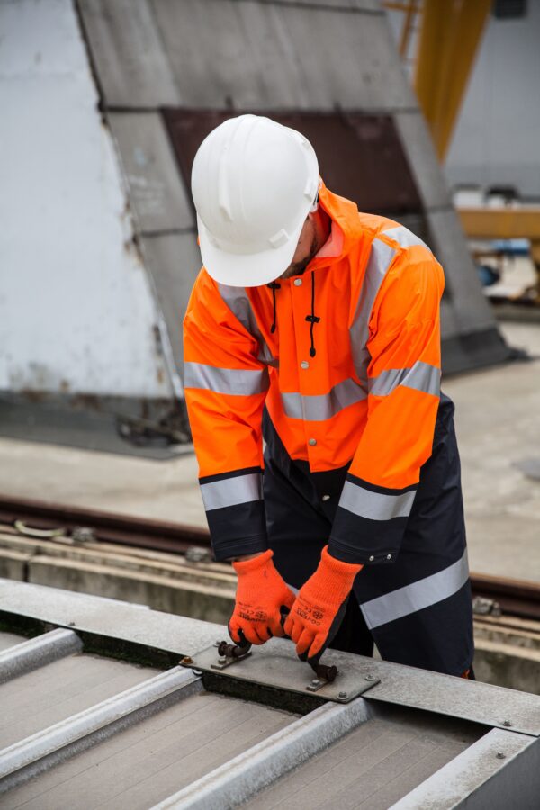 Construction worker in high-visibility PPE securing metal framework