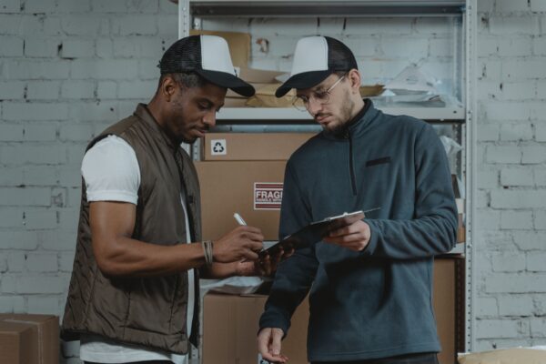 Two warehouse workers reviewing paperwork together in a storage area